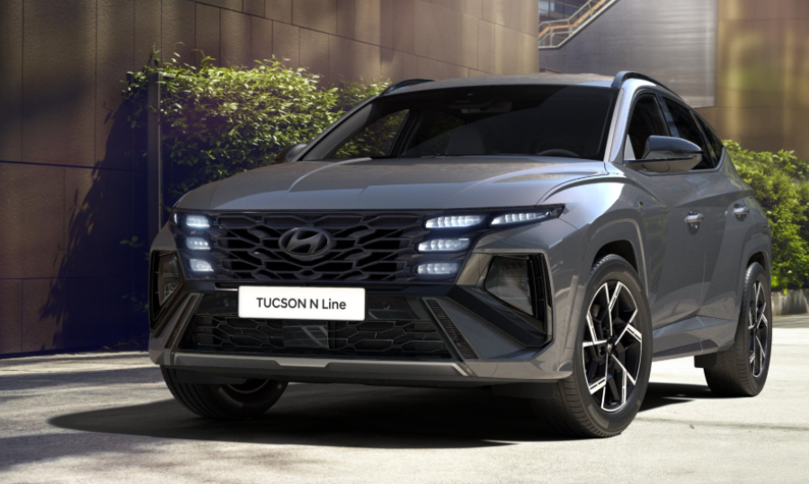 Grauer Hyundai Tucson N Line SUV steht vor einem modernen Gebäude.