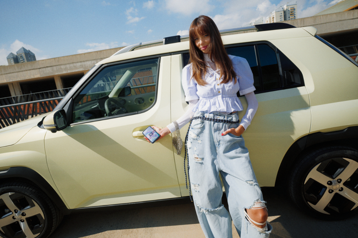 Eine Frau lehnt sich an einen hellen Hyundai Inster