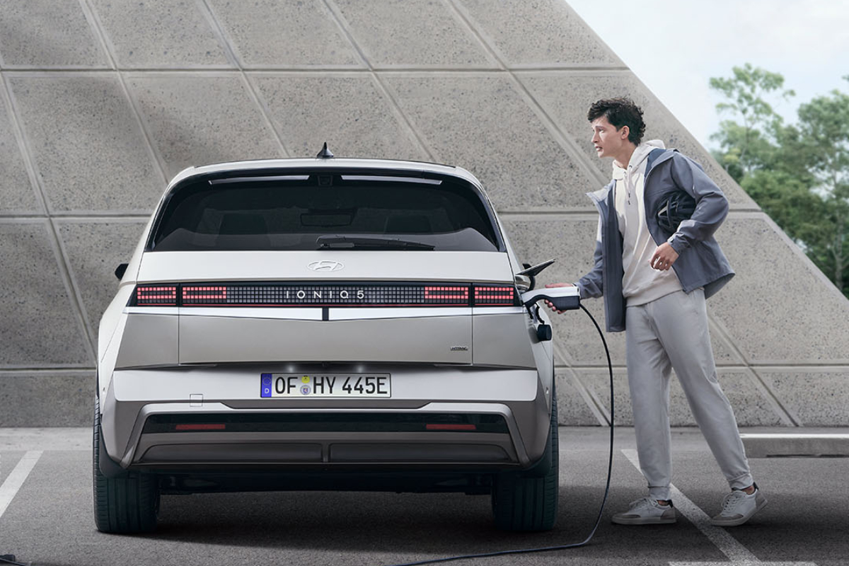 Ein Mann hält ein Ladekabel und lädt einen weißen Hyundai Ioniq 5