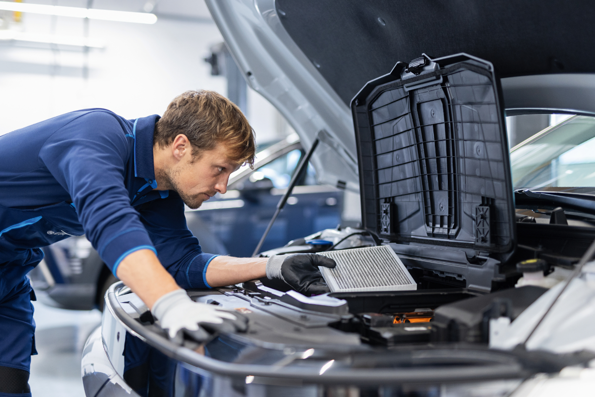 Kfz-Mitarbeiter, der am Motor etwas prüft