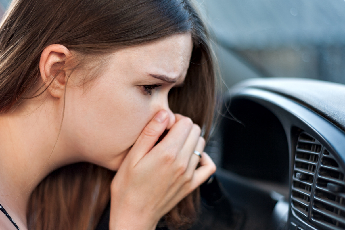 eine Frau, die sich die Nase zuhält im Auto 