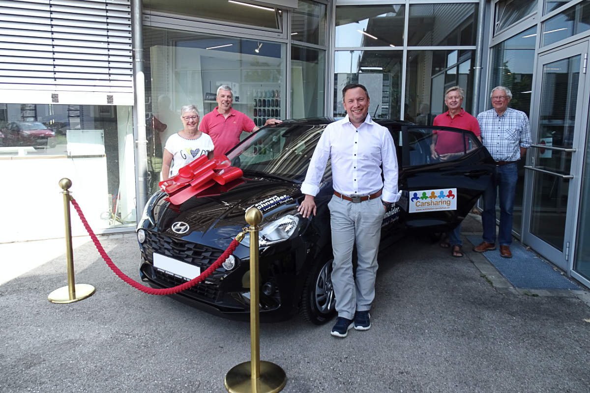 Mitarbeiter des Autohauses Schneider und des Autoteile Landshut e.V. stehen neben einem Auto des Autohauses