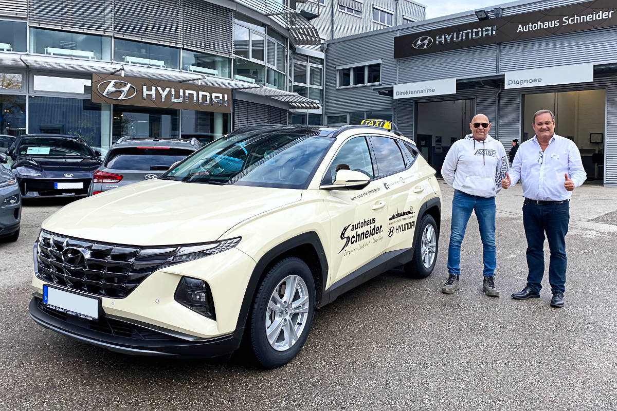 Peter Baur übergibt Karl-Heinz Schwedas den neuen Hyundai TUCSON. Beide stehen nebeneinander am Fahrzeug
