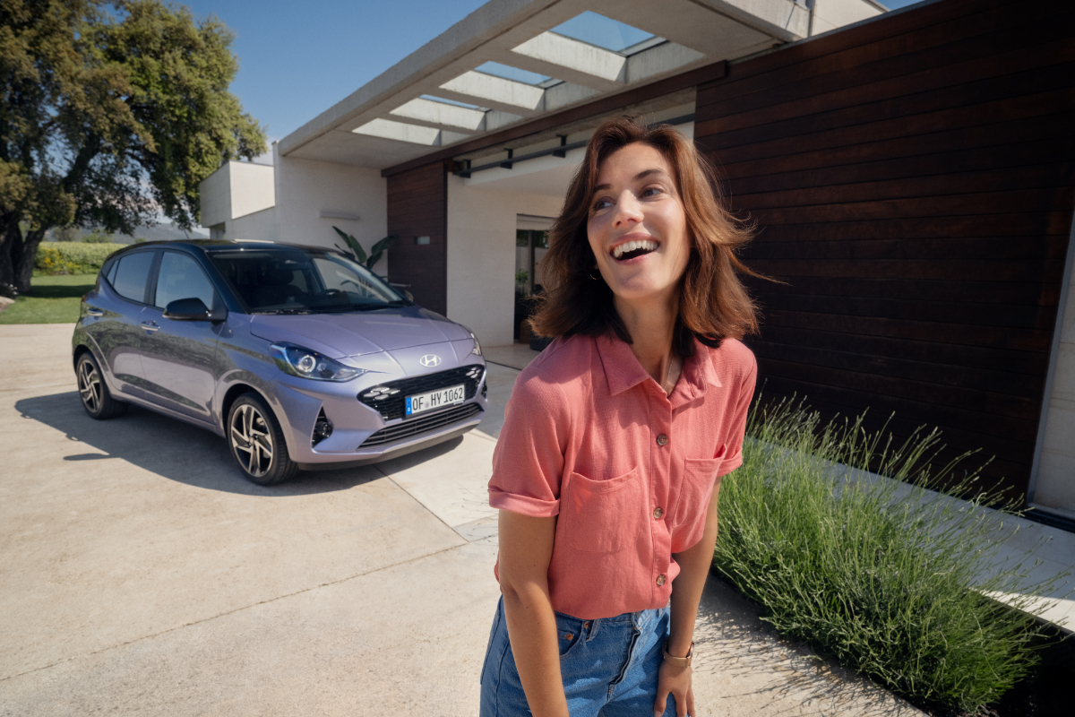 glückliche Frau steht vor einem grauen i10