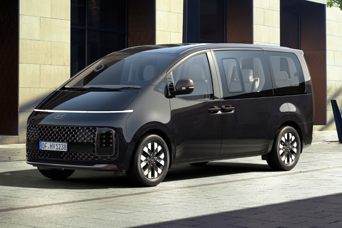 Schwarze Hyundai Staria vor einem modernen Gebäude.