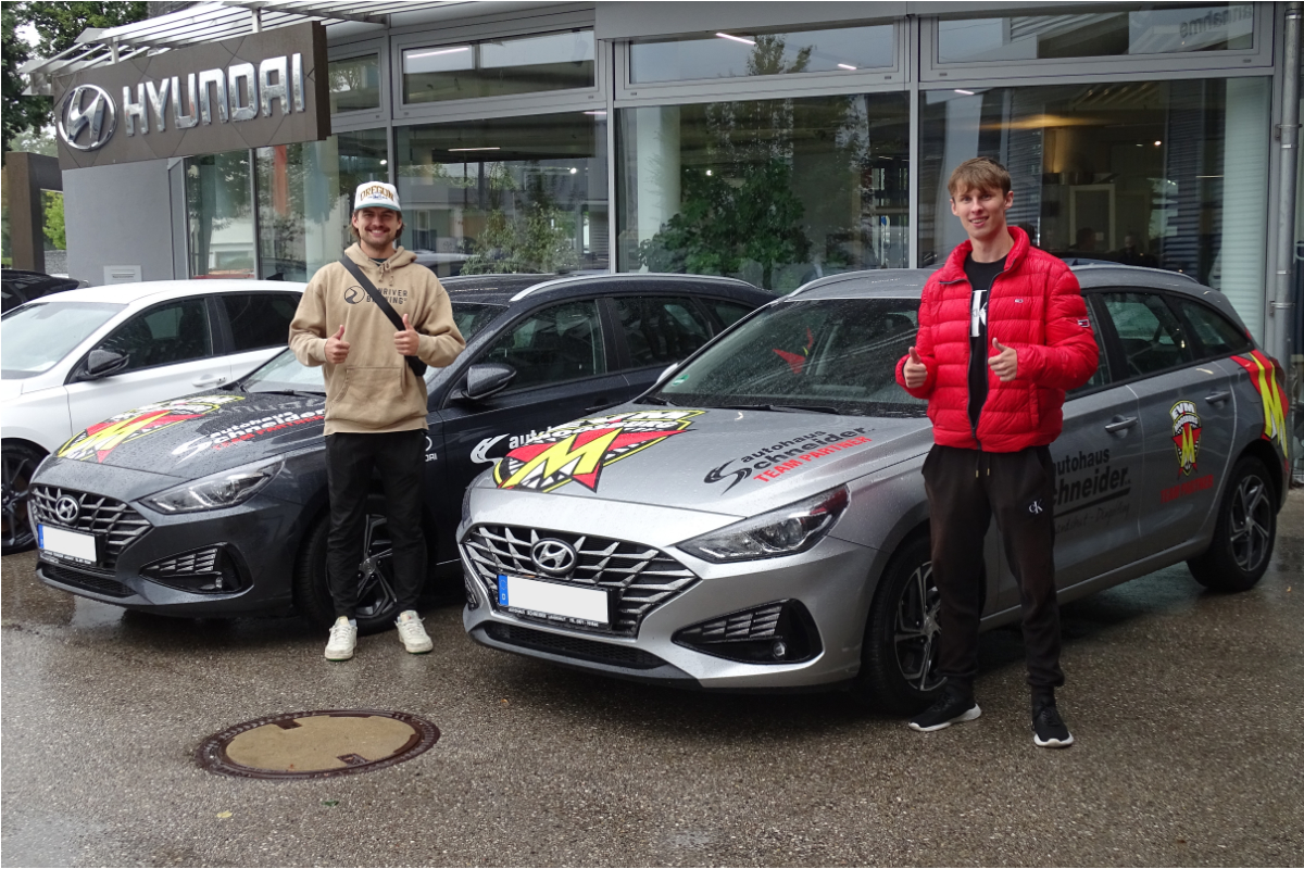 zwei EVM Mitglieder stehen neben ihren neuen Autos