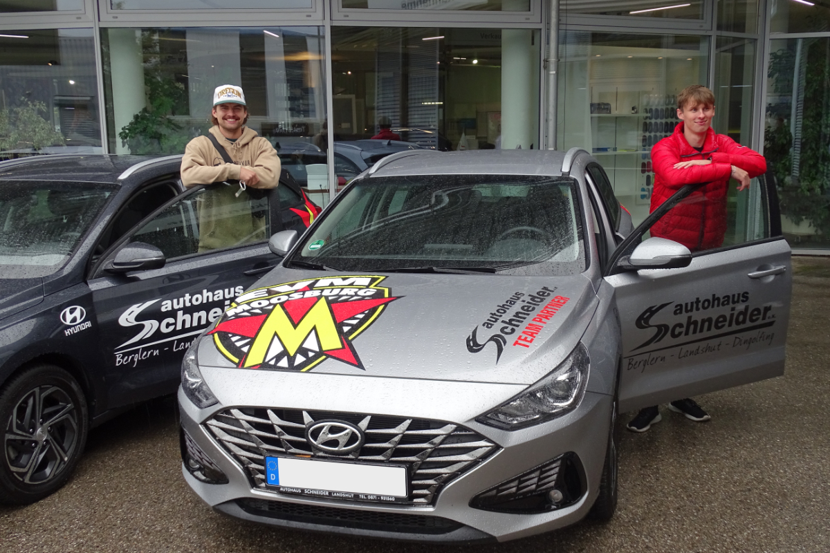 zwei EVM Mitglieder stehen neben ihren neuen Autos 